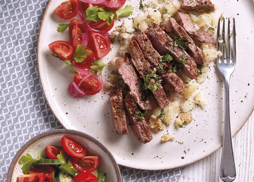 Sliced meat, potatoes and tomatoes on a plate