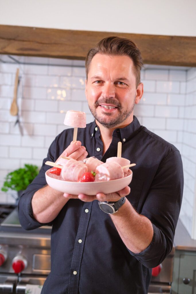 Jimmy Doherty smiling and presenting a bowl of milk and berry lollies